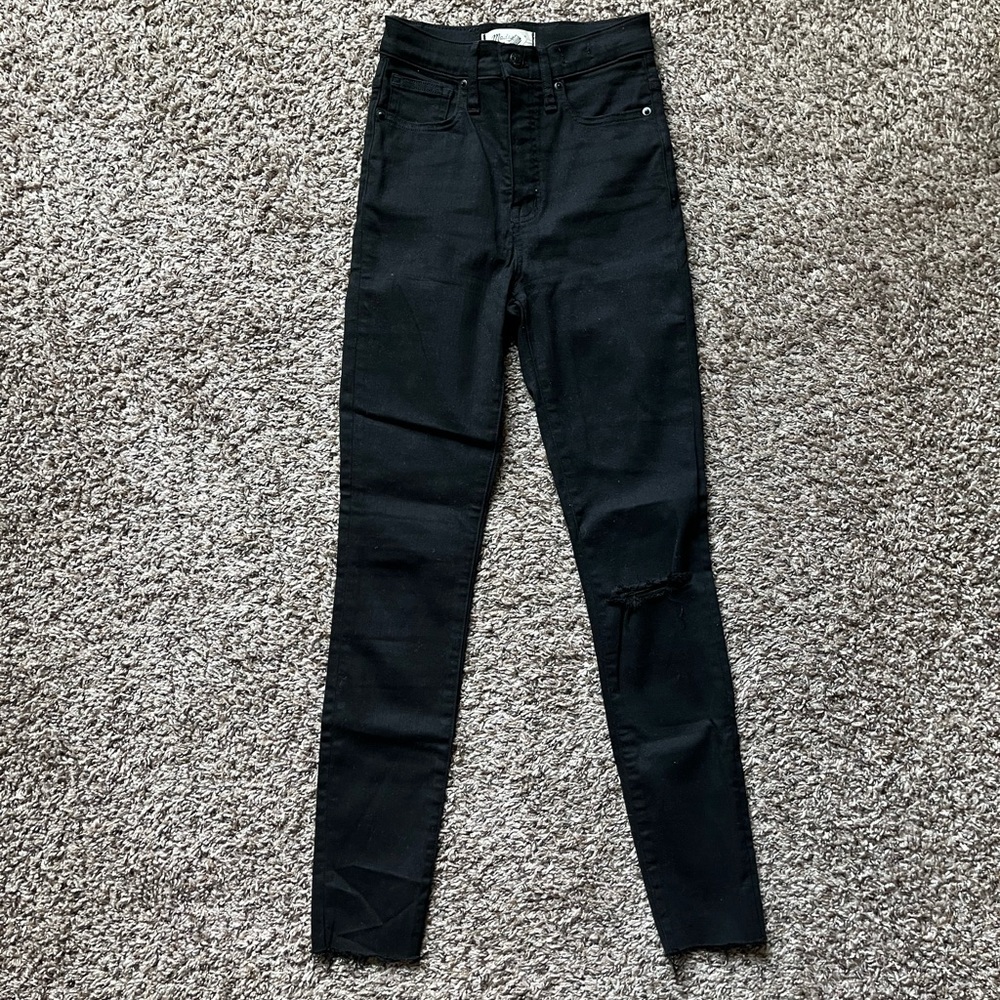 Black 11” rise Skinny jeans with raw hem and knee rip.